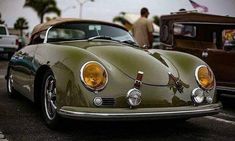 an old green sports car parked in a parking lot