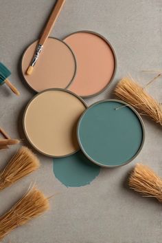 four different shades of paint sitting on top of each other next to brushes and straws