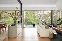 a living room filled with furniture next to a large glass window covered in greenery