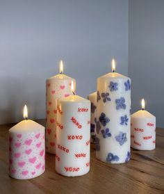 four candles with different designs on them sitting on a table