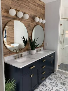 a bathroom with two sinks, mirrors and a plant in the middle of the room