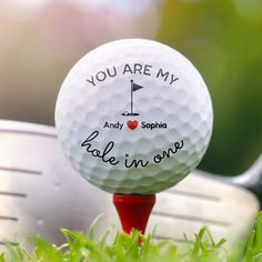 a golf ball with the words you are my hole in one on it sitting next to a pair of golf clubs