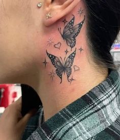 a woman with a butterfly tattoo on her neck and behind her ear is looking at the camera