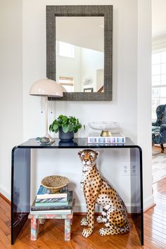 a cheetah statue sitting on top of a table next to a mirror and lamp