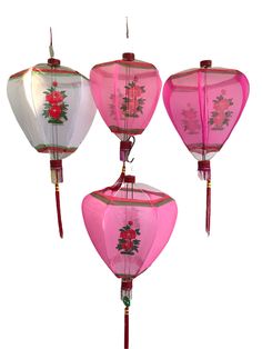 three pink and white chinese lanterns with flowers on the bottom one is hanging from a string