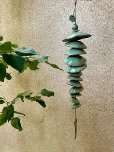 a wind chime hanging from a tree next to a plant with leaves on it