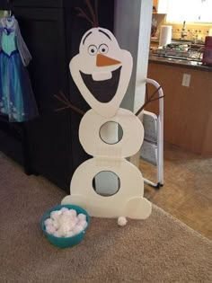 a cardboard snowman made to look like it is standing next to a bowl of marshmallows