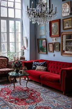 a living room with red couches, chandelier and pictures on the wall