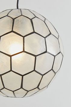 a white light hanging from the ceiling in front of a gray wall with a circular pattern on it