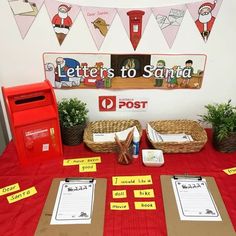 a red table topped with mail boxes and post office signs next to potted plants