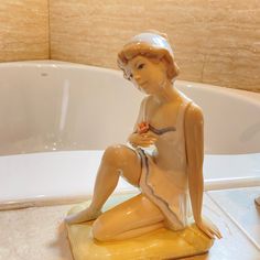 a statue of a woman sitting in front of a bath tub