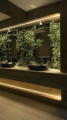 a bathroom with plants on the wall and lights in the bathtub area, along with two sinks