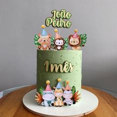 a birthday cake decorated with animals and the words mes on top is sitting on a table