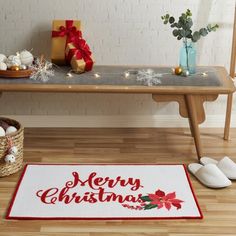 a merry christmas doormat with poinsettis and presents on the floor next to it