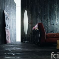 a living room with wood paneling and a red chair in the corner next to a white floor lamp