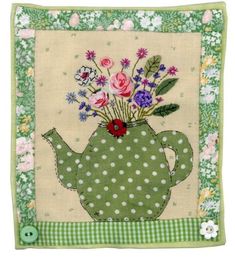 a green teapot filled with flowers on top of a white and green checkered table cloth