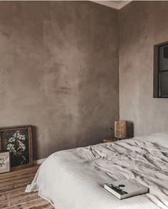 a white bed sitting in a bedroom next to a window and framed pictures on the wall