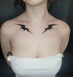 a woman wearing a white dress with black bats tattooed on her chest and upper half