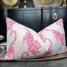 a pink and white pillow sitting on top of a metal tray next to a dresser