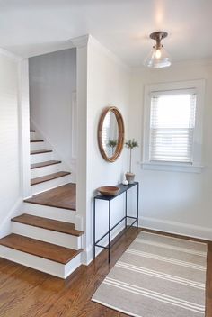 there is a mirror on the wall next to some stairs and a table with a potted plant