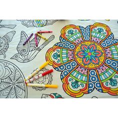 several crayons are laying on top of an adult coloring book with intricate designs