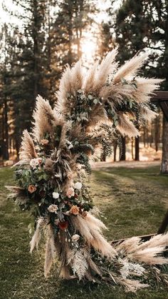 a wedding arch decorated with dried flowers and pamodia leaves in front of trees