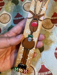 a hand holding a wooden stick with a reindeer on it