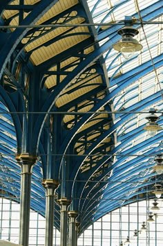 the inside of a train station with blue and white lines on the ceiling, lights hanging from the ceiling