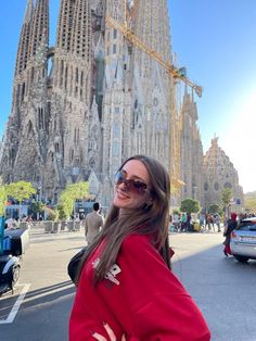 a woman standing in front of a very tall building with many spires on it