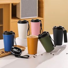 several different colored cups sitting on top of a table next to a wooden spoon and cup holder