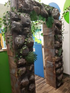 an arch made out of rocks with plants growing on it in the middle of a room