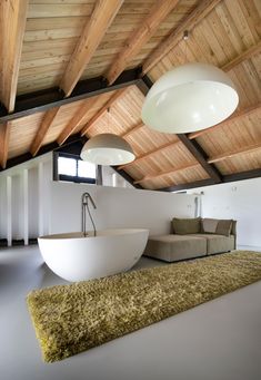 a large white bath tub sitting in the middle of a living room next to a couch