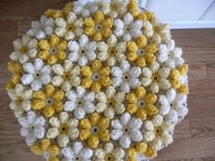 a yellow and white crocheted table top on a wooden floor with a door in the background