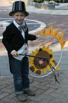 a young boy wearing a top hat and holding a metal ring with a lion on it