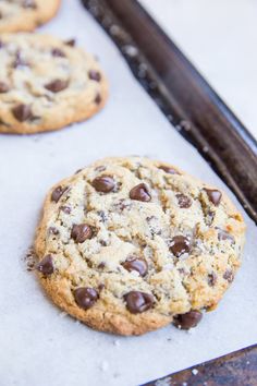 two chocolate chip cookies sitting on top of a cookie sheet