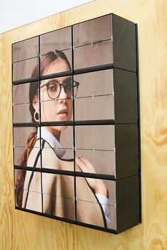 a woman wearing glasses is on a large screen mounted to the side of a wall