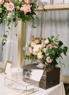 a table with flowers on it and a gift box under the flower centerpieces