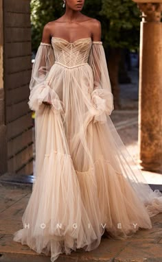 a woman in an off the shoulder dress is standing on a stone walkway with her hands behind her back