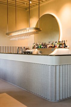 a bar with several bottles on it and a circular mirror hanging above the bar area