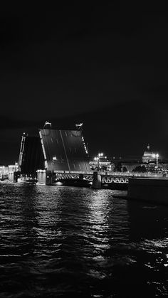 a black and white photo of a city at night with lights reflecting off the water