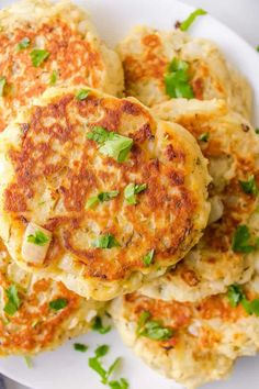 three crab cakes on a white plate with green garnishes and parsley