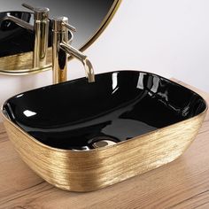 a black and gold bathroom sink sitting on top of a wooden counter