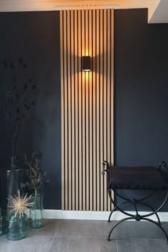 a chair and vases in front of a wall with vertical striped paneling on it