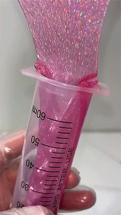 a person holding a pink plastic tube with glitter on it and measuring the inside out