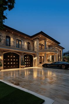 a car is parked in front of a large house with lights on it's windows