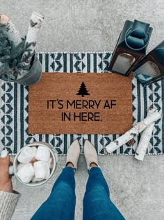 a person standing next to a door mat that says merry christmas ya filthy animals