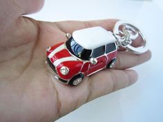 a small red and white car keychain sitting on top of a person's hand