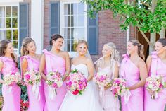 a group of women standing next to each other wearing pink dresses and holding bouquets