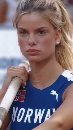 a woman holding a baseball bat on top of her shoulder and looking at the camera