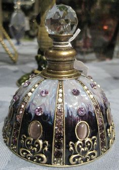 an ornately decorated glass and gold candle holder on a white tablecloth with other decorative items in the background